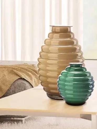 Due vasi in vetro a cerchi sovrapposti, color sabbia e verde, su un tavolino in soggiorno
